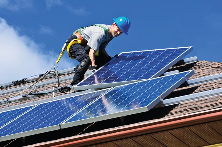 Man installing alternative energy photovoltaic solar panels on roof