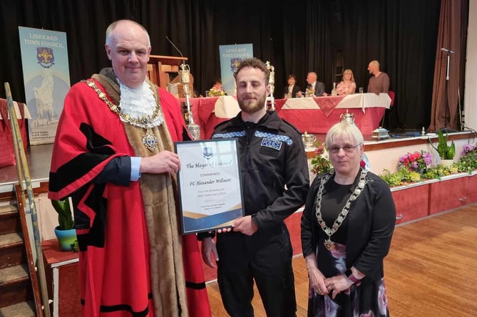 Outgoing mayor Simon Cassidy presents PC Alex Willmott with a bravery commendation. PC Willmott, who was off-duty at the time, alongside two members of the public, apprehended an offender following an armed robbery at a shop in Liskeard. Pictured right is now mayor Councillor Christina Whitty. (Picture: Terry Whitty)