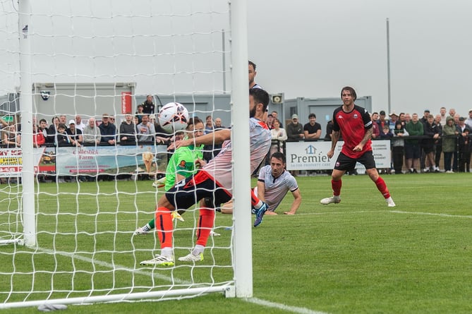 Tyler Harvey (back of picture) watches on as his strike nestles into the far corner of the Dorking net.