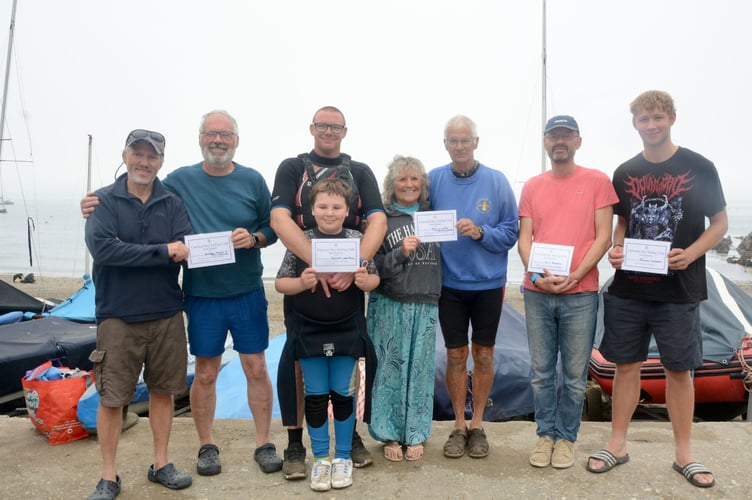 The winners of certificates presented after the races.
From left: Third overall Phill Holmes and Andrew Molloy who sailed Andrew’s 2000, club commodore Mark Lentell who presented the certificates, with son Will in front, (who gained his certificate for completing his first Cawsand Bay Sailing Club regatta), Penny Knowles and Ian Turpitt who were second overall in Ian’s 2000 and winner Guy Pearson who won in his Laser Radial. Finlay Morgan, far right, won the standard Laser class.