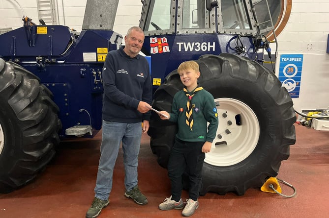 Jack from the 1st Looe Cubs hands over a cheque for £370 to Geoff Gee of the Looe RNLI