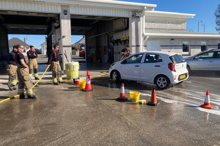 Firefighters from Saltash taking part in their charity car wash helping to raise funds for The Fire Fighters Charity